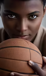a woman holding a basketball while looking into the camera
