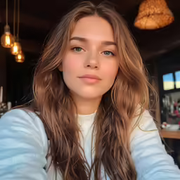 a girl with long, wavy hair looks at the camera