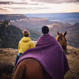 two people are on horseback in a blanket near mountains