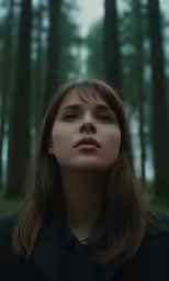 a young woman with long hair looking up in a forest