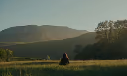 the woman is sitting in the field alone