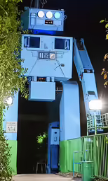 a giant robot statue at night next to some trees