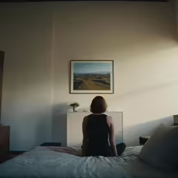 a person sitting on top of a bed looking at the sun