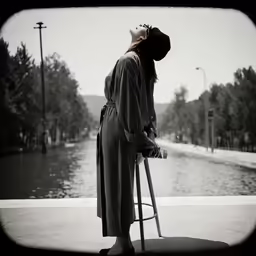 an asian woman looking at a water canal with a stool