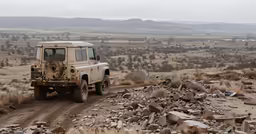 a jeep driving down a dirt road surrounded by rocks