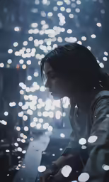 a person sitting on a ledge in front of a street with lots of lights