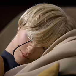 a blonde haired woman with glasses lying down