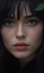 a woman with dark hair and blue eyes wearing a black suit
