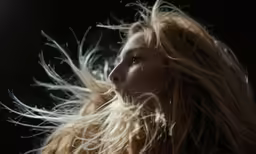 the woman with long blonde hair is blowing in the wind