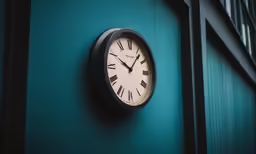 a clock mounted to a green wall outside of a building