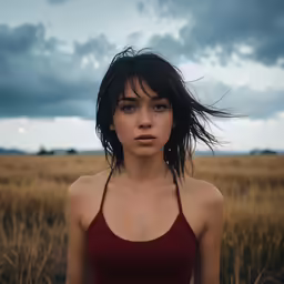 a woman wearing red is standing in the middle of a field
