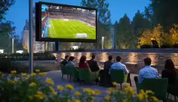 several people sitting in a room watching tennis on large tv