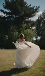 a woman in a dress is walking through a grassy field