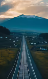 a train tracks stretches into the distance to the sky with a snowy mountains in the background