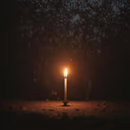 a candle on the ground in the dark
