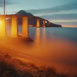 a foggy sunrise near an old bridge over the water