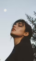 a woman standing up and praying with her eyes closed