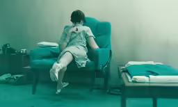 woman in chair sitting on table with small green object near it
