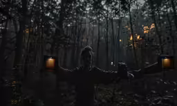 man standing in the woods holding lights in both his hands