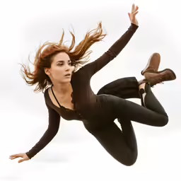 a woman is suspended from a wire with one hand