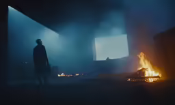 a man standing in a dark room with the tv on