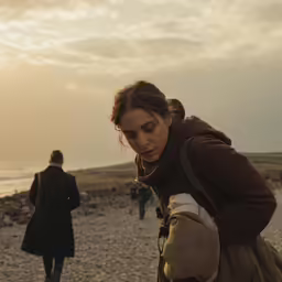 a girl standing on the beach and looking at her phone