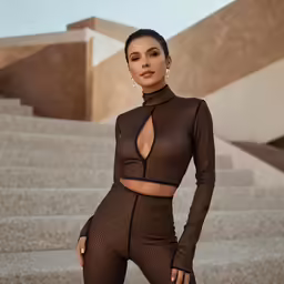 a woman in sheer clothing is posing in front of some stairs