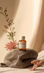 someone is holding their hand over the bottle of oil on the bed