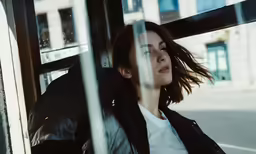 woman with windblwing hair leaning out of window