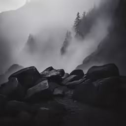 fog covers the mountains surrounding some rocks and trees