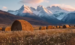 a large field filled with hay bales surrounded by mountains