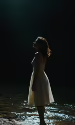 a woman standing alone in water at night