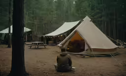 a person sitting on the ground near tents