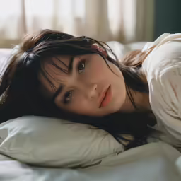 the young woman is laying on her side in a bed