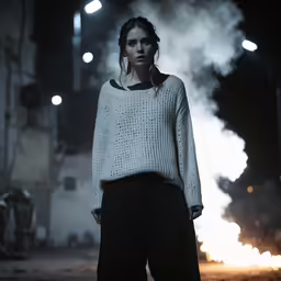 a woman in white sweater standing on street at night
