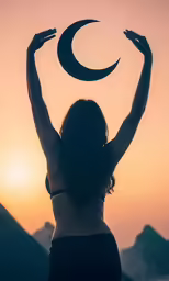 a woman in the middle of the sunset holding her arms in the air