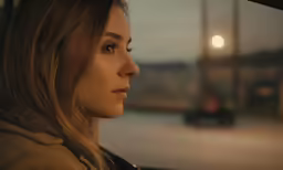 woman looking off from a car window in the evening