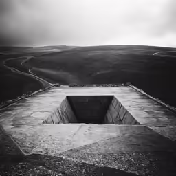 black and white photograph of an empty pit in a stone wall