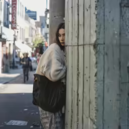 a woman leans against the side of a building
