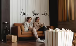 two women sitting on the couch and watching a television