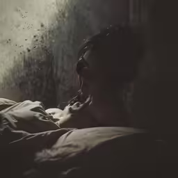 a girl sitting on her bed in the dark