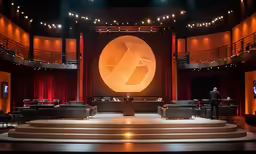 a stage set with two chairs, one sitting and the other standing