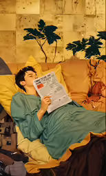 man reading paper while lying down in bed