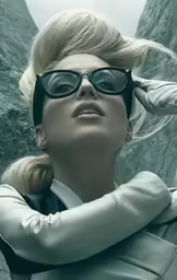 a woman in black sunglasses looking off into the distance