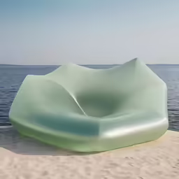 a sculpture sitting on top of a sandy beach next to the ocean