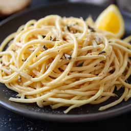 a plate full of pasta and a lemon wedge