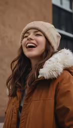 a woman laughing in front of a tan building