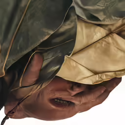 a person peeking out from under a green coat