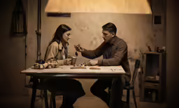 the couple are sitting at the table eating pizza