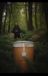a woman is looking at a barrel in the woods